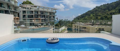 Una piscina al aire libre, sillones reclinables de piscina