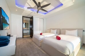 Une chambre d’hôtel moderne avec deux lits, un ventilateur de plafond et une grande fenêtre.