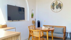 Ein modernes Wohnzimmer mit einem Holzespeisetisch, zwei Korbstühlen, einer Couch und einem flachbildfernseher an der Wand.