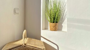 Ein Korbwägelchen steht auf einem Holztisch, ein Lichtschalter an der Wand und ein Blumentopf in einem Fenster.