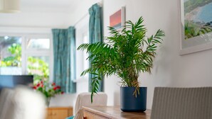 Ein Zimmer mit einem Holzkasten, einer Topfpflanze, einem Stuhl und einem Bild an der Wand.