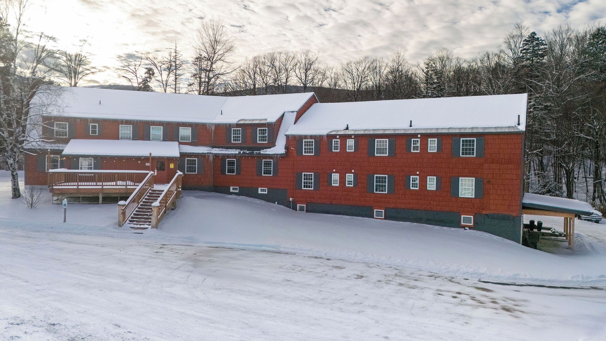 A large, multi-story building with a snow-covered roof and a wooden deck.