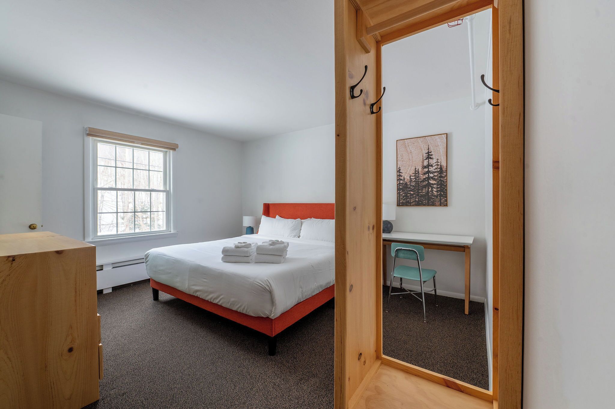A bedroom with a bed, a desk, a chair, and a window.