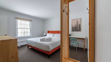 A bedroom with a bed, a desk, a chair, and a window.