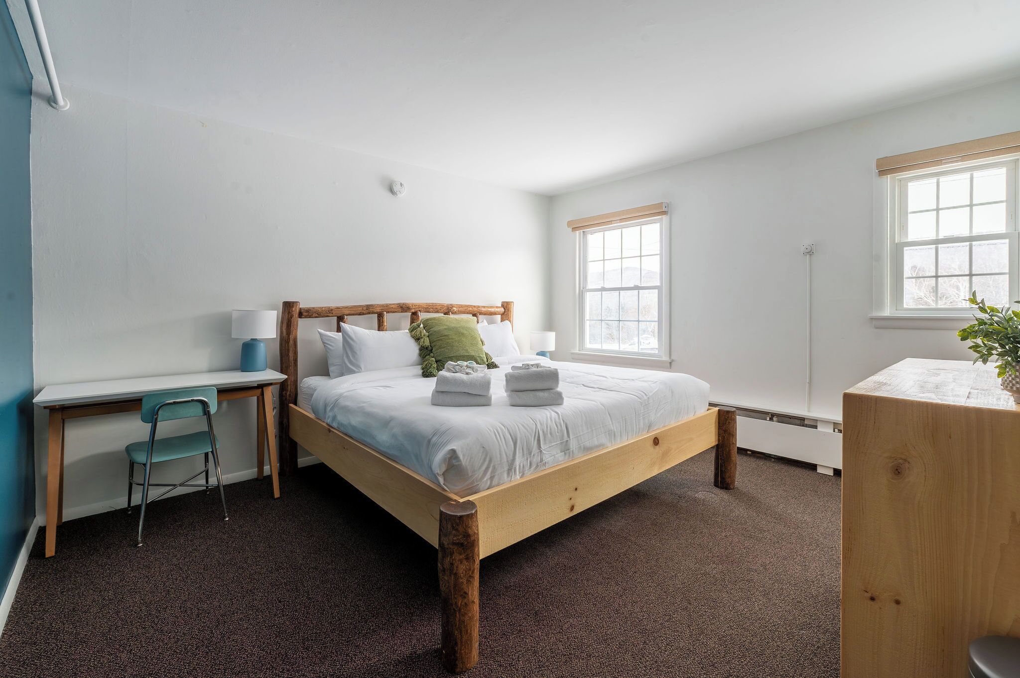 Un dormitorio con cama de madera, un escritorio y una silla.