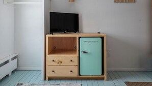A room with a wooden cabinet containing a television and a vintage-style mini-fridge. - Killington Haus (Killington)