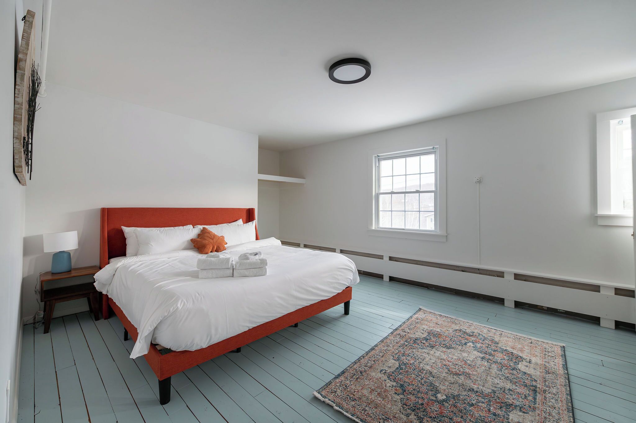 Une chambre à coucher avec un lit, une table de chevet, une fenêtre et un radiateur.