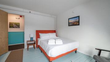 A neatly arranged bedroom with a bed, bedside table, and a small chair.