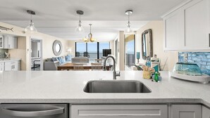 Cozinha moderna com uma ilha grande, eletrodomésticos de aço inoxidável e vista para o exterior.