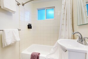 A bathroom with a bathtub, a sink, and a window.