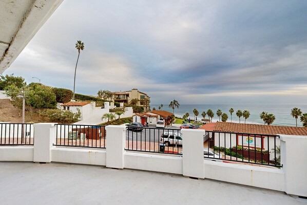 A coastal residential area with a white building, a view of the ocean, and palm trees.