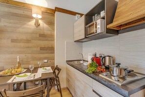 Una cucina moderna con mobili in legno, piano cottura integrato e zona pranzo con tavolo apparecchiato per due persone.