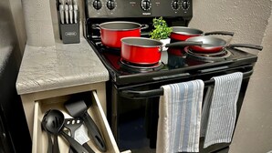 A compact kitchen with a stove, pots, and a utensil holder. - Pool, A+ location, washer/dryer, LongStayDiscounts (Sherman)