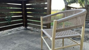 A wicker chair with a metal frame, positioned on a concrete surface near a wooden fence. - Pool, A+ location, washer/dryer, LongStayDiscounts (Sherman)