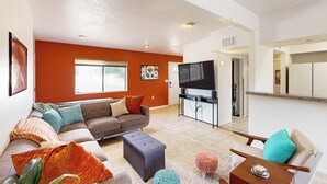 A living room with a sofa, ottoman, and a television. - Dog-Friendly Home w/ Fenced Yard in Sierra Vista! (Sierra Vista)