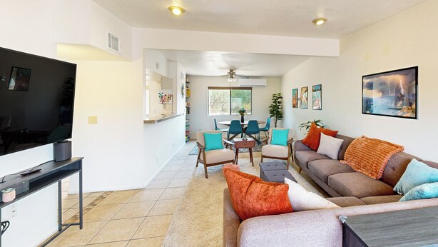 A modern living room with a flat-screen TV, a sofa, and a dining area with chairs and a table. - Dog-Friendly Home w/ Fenced Yard in Sierra Vista! (Sierra Vista)
