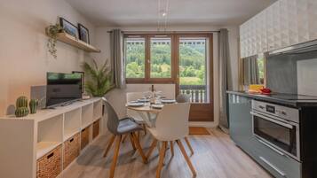 A modern kitchen with a dining area, a TV, and a view of the outdoors.