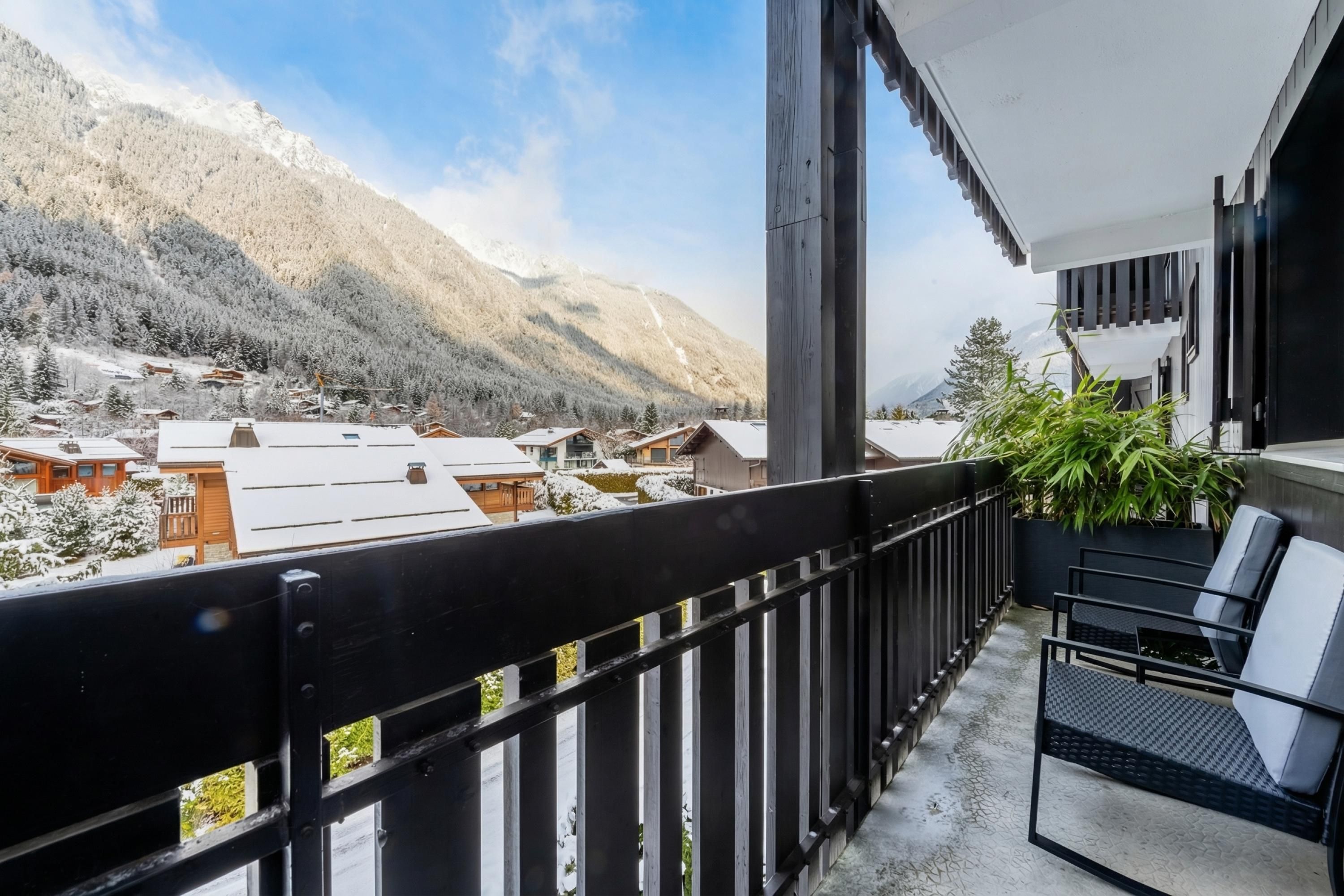 A balcony with a view of snow-covered mountains and a village below.