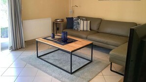 A living room with a sofa, a coffee table, and a TV. - Ferienhaus in Burhave (Butjadingen)