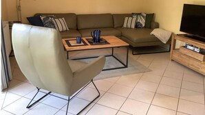 A living room with a sofa, a coffee table, a chair, a television, and a painting on the wall. - Ferienhaus in Burhave (Butjadingen)