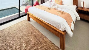 A bedroom with a large window, a bed with a wooden headboard, a bedside table, and a small bedside lamp. - Villa Eclipse B2 (Jimbaran)