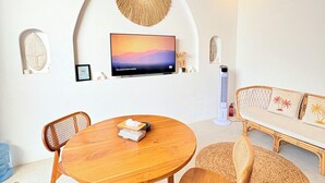 A modern living room with a wooden dining table, two chairs, a sofa, and a TV mounted on the wall. - Villa Eclipse B2 (Jimbaran)