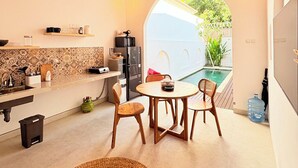 A modern kitchen with a dining area, a large water dispenser, and a view of a swimming pool. - Villa Eclipse B2 (Jimbaran)