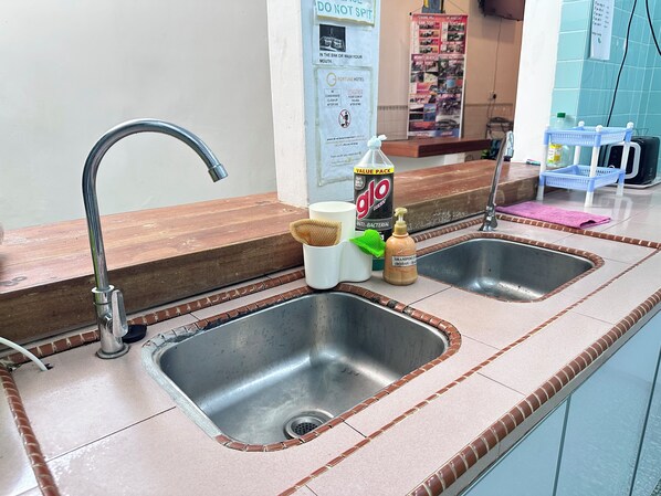 A hotel bathroom with two sinks, a mirror, and toiletries including a bottle of shampoo and a bottle of lotion. - Rangoon Residence 26 (George Town)