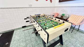 A foosball table in a room with tiled walls and a green floor.