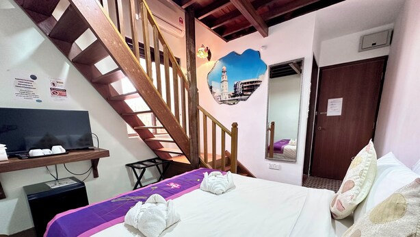 Une chambre d’hôtel avec un lit, une télévision, un bureau, un escalier et un miroir.