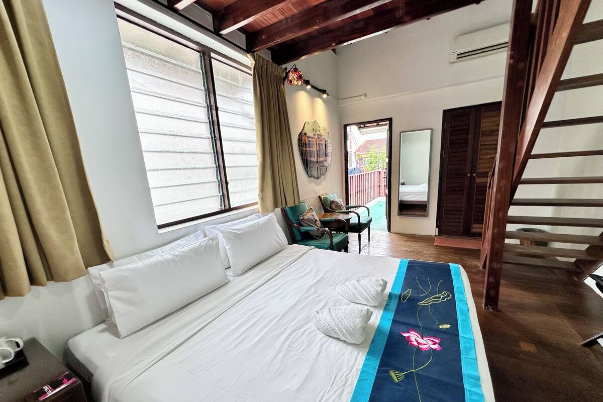 A bedroom with a bed, a desk, and a staircase.