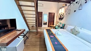 A bedroom with a bed, a desk, a chair, a staircase, and a door. - Rangoon Residence 26 (George Town)