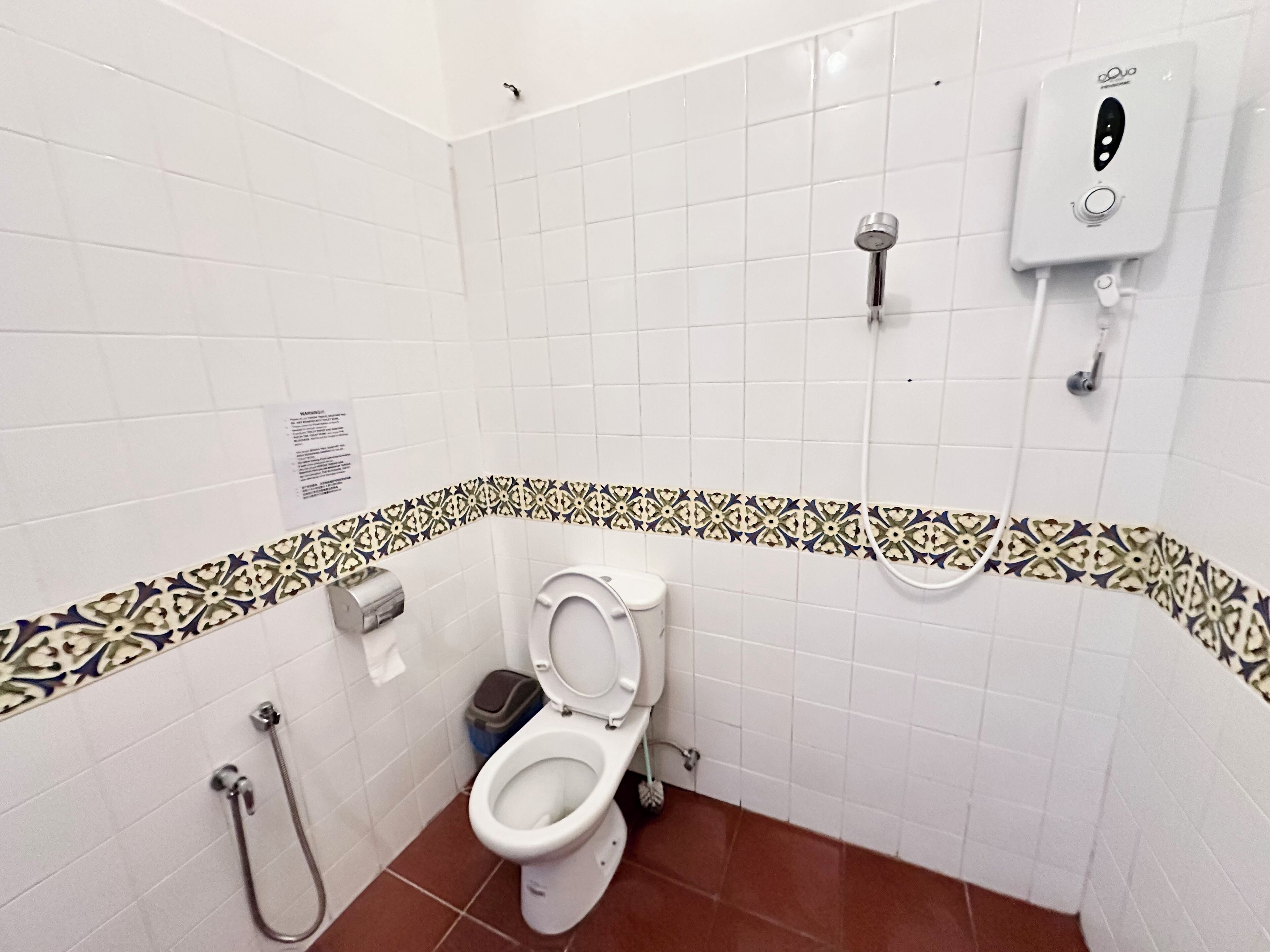 A bathroom with a toilet, a shower, and a hand dryer.