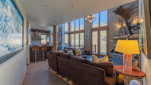 A spacious living area with a large sofa, a dining table, and a kitchen in the background. - Ski-in/ski-out 4-bedroom townhome in Crested Butte! (Gunnison)