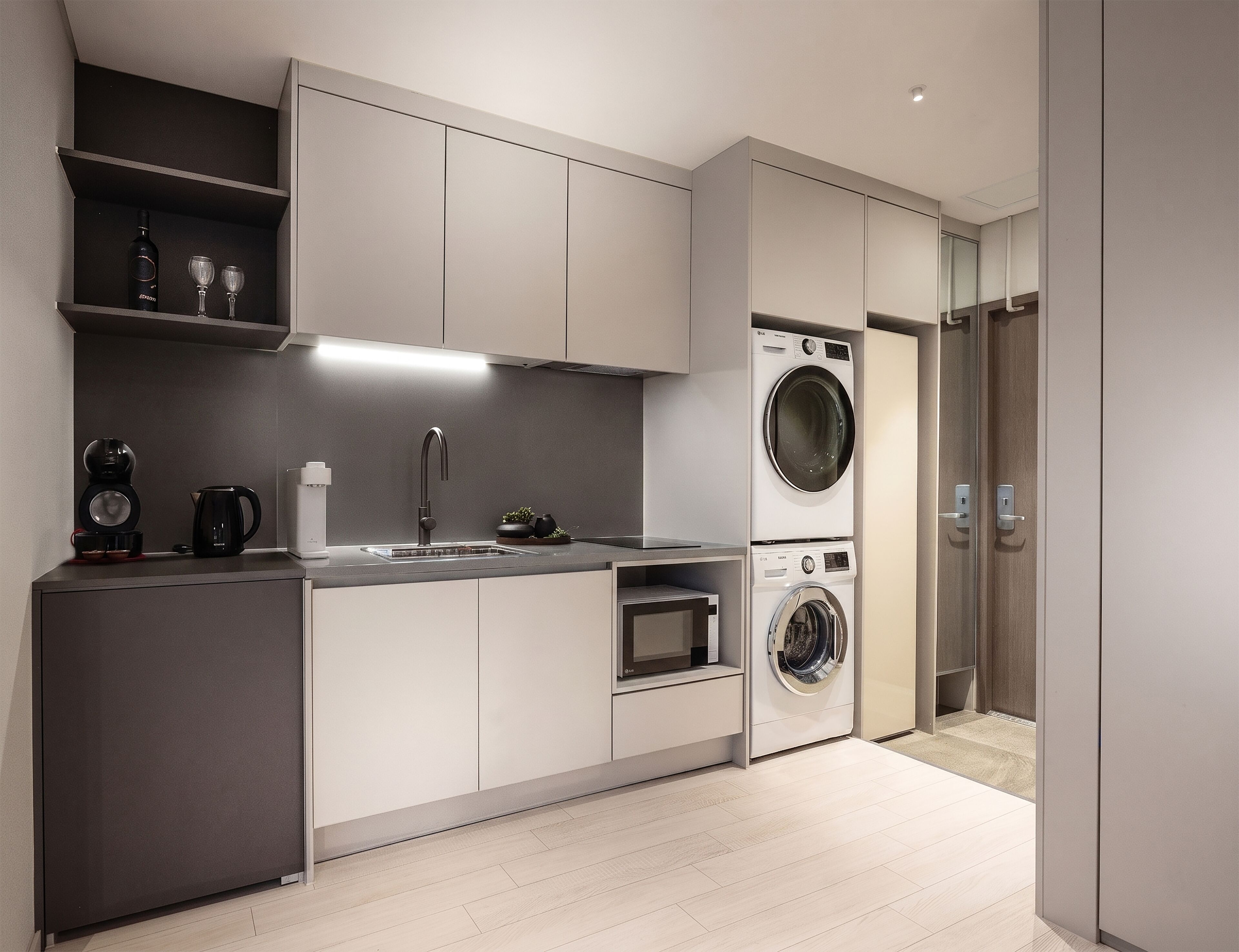 Una cocina moderna con lavadora incorporada, cafetera y pileta.