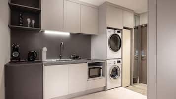 Una cocina moderna con lavadora incorporada, cafetera y pileta.