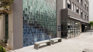 Un edificio moderno con una amplia entrada en arco, fachada de azulejos y un letrero que dice 'Outdoors'.