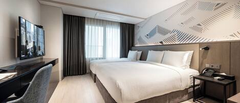 Una habitación de hotel moderna con una cama grande, un escritorio con silla, televisión y un papel tapiz estampado.