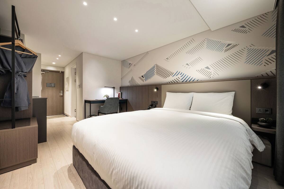 Een moderne hotelkamer met een groot bed, een bureau en een kledingkast.