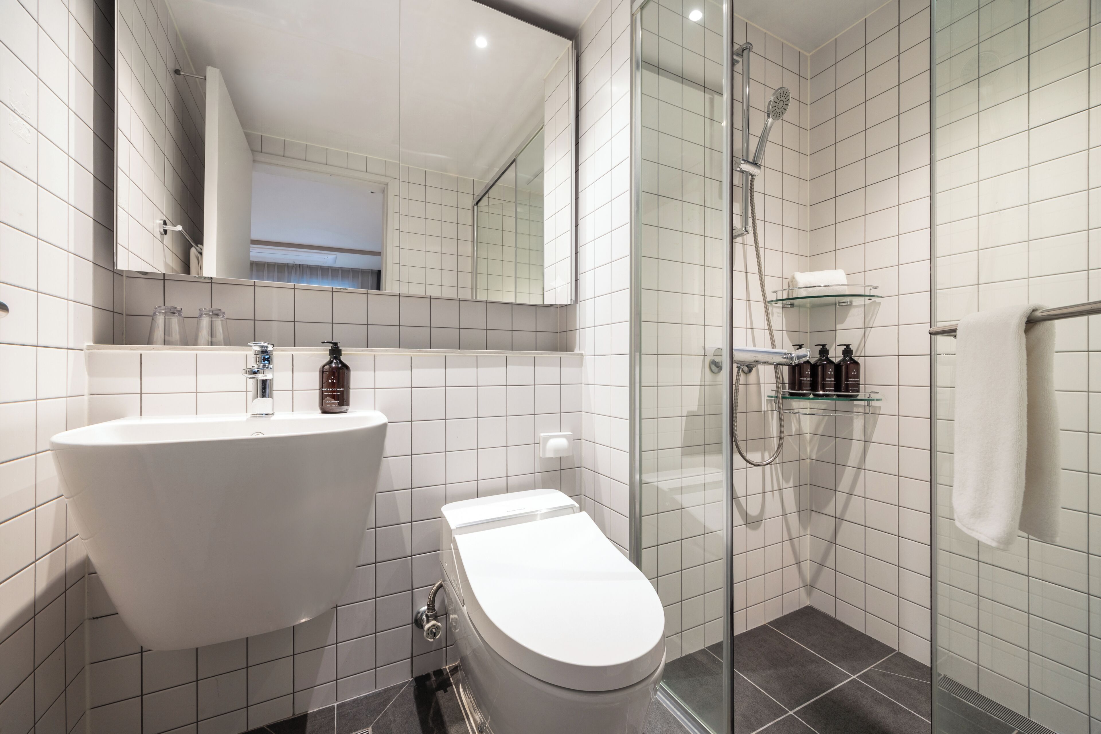 Un baño con lavamanos blanco, inodoro y cabina de ducha de vidrio.