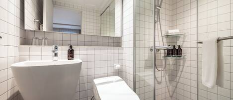 A bathroom with a white sink, toilet, and glass shower enclosure.