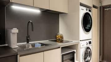 A modern kitchen with a built-in washer and dryer, a stainless steel sink, and a compact oven.