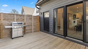 A patio with a barbecue grill, a sliding glass door leading to an interior space, and a wooden fence. - Renovated home minutes from downtown Indianapolis! (Indianapolis)