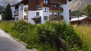 A multi-story hotel with balconies, surrounded by mountains and greenery. - Achat 4 by Interhome (Saas-Fee)