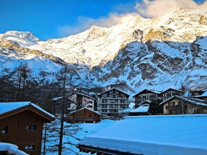 A mountain lodge with multiple wooden buildings, snow-covered surroundings, and a backdrop of snow-capped mountains. - Achat 4 by Interhome (Saas-Fee)