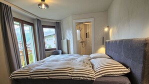 A modern bedroom with a large bed, a view of a balcony, and a shower area. - Achat 4 by Interhome (Saas-Fee)