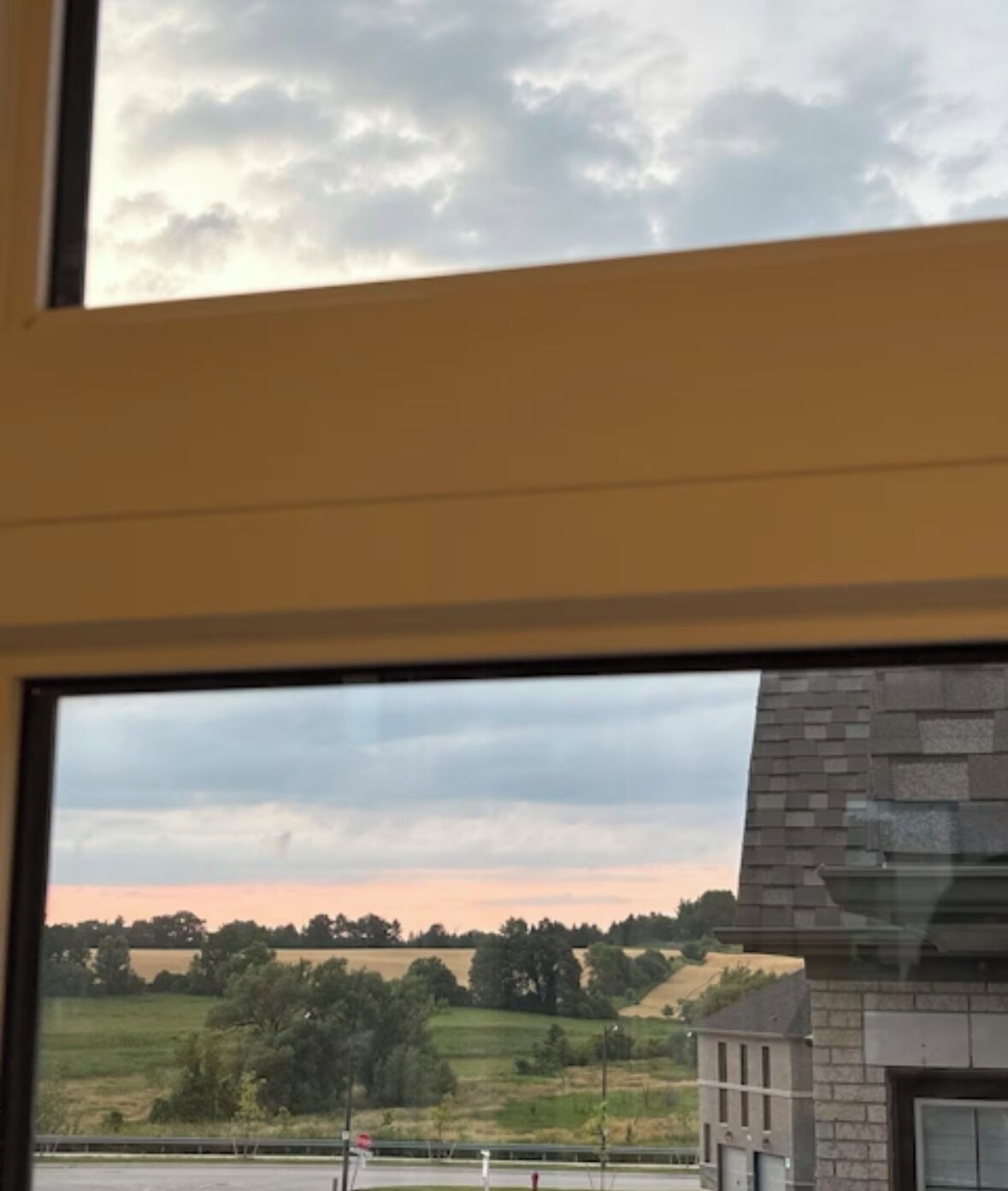 A view through a window with a clear sky and a landscape of fields and trees.