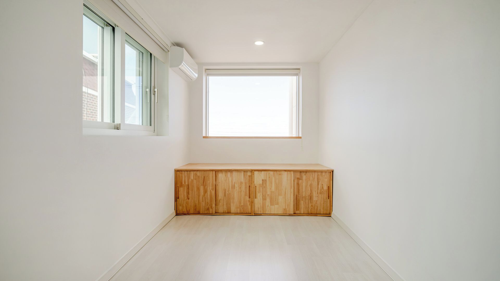 A room with a wooden bench, a window, and a ceiling light.