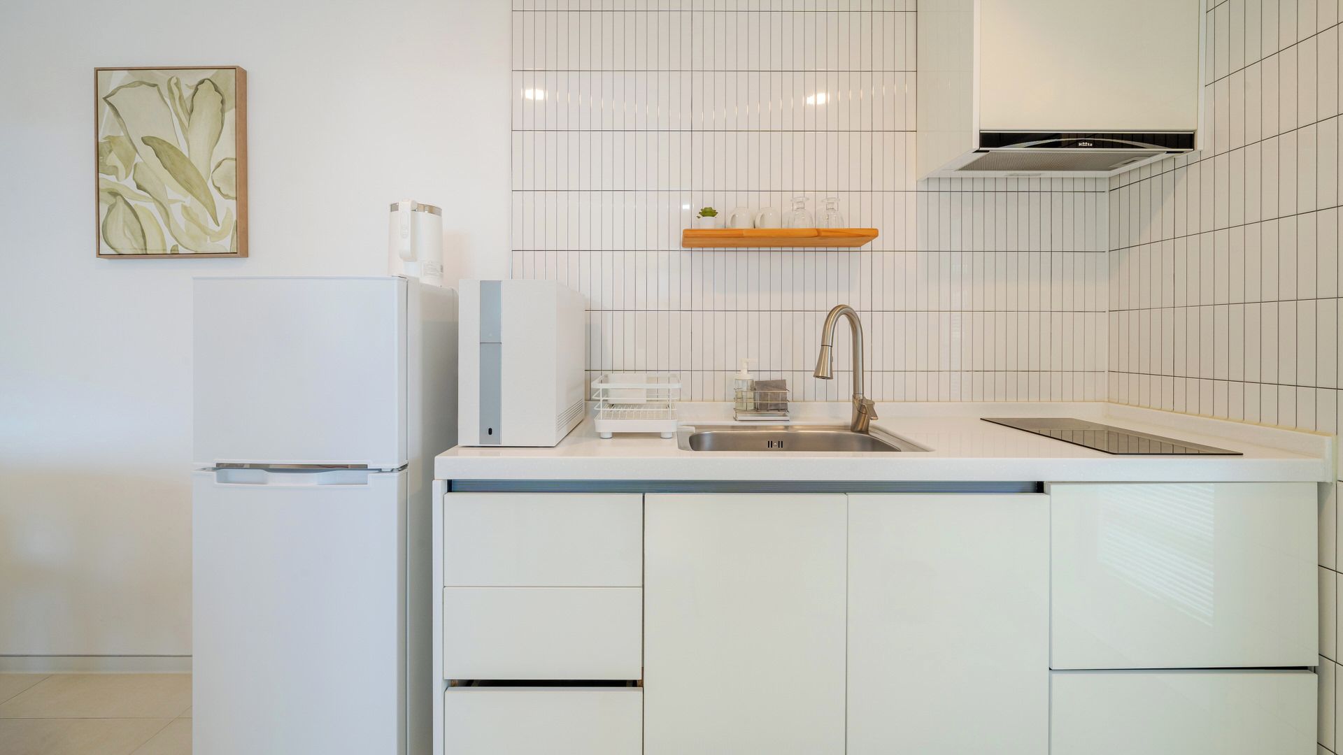 Una cocina moderna con armarios blancos, un lavamanos de acero inoxidable y un horno empotrado.