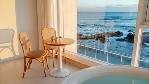 A balcony with a view of the ocean, a round table with two chairs, and a bathtub. - Donghae Badadam Ocean View Spa Pension (Donghae)